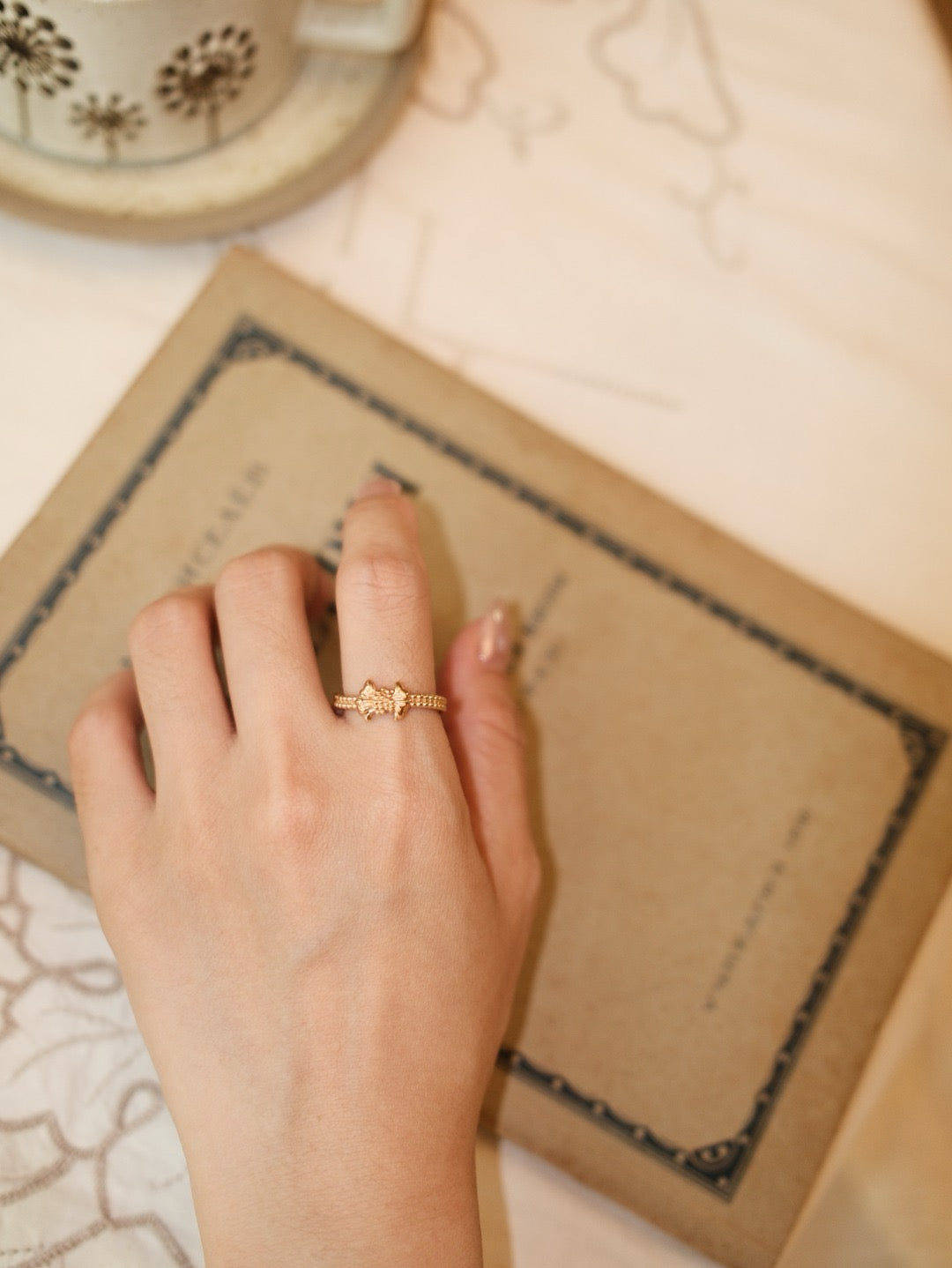 Gilded bow ring. Its crinkled texture brings an innate vintage charm, accented with dangling teardrop zircon stones that embody sophisticated grace.