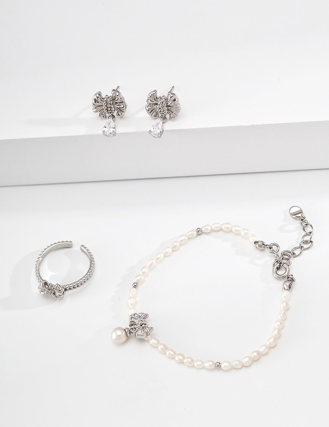 Gilded bow ring. Its crinkled texture brings an innate vintage charm, accented with dangling teardrop zircon stones that embody sophisticated grace.