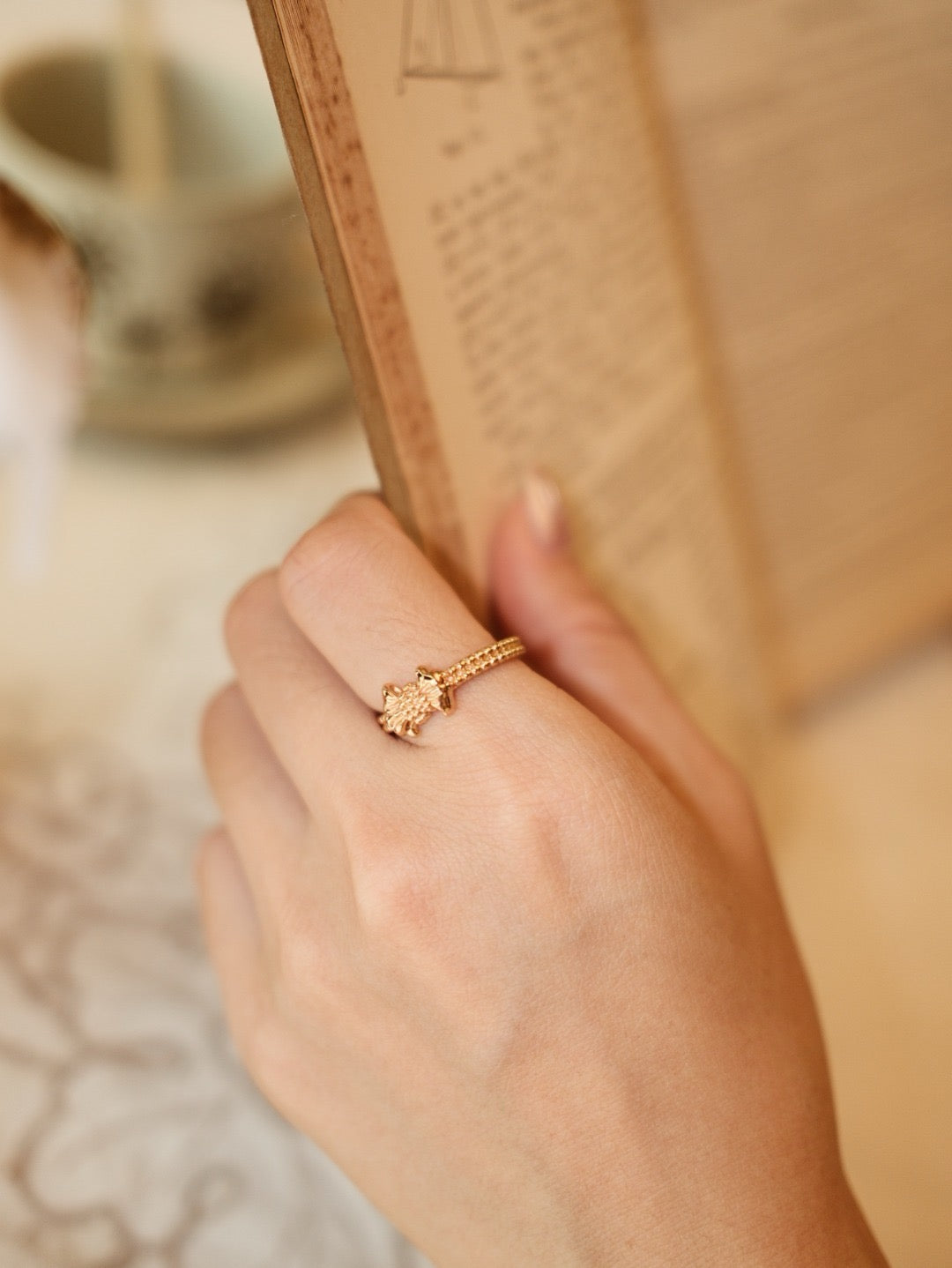 Gilded bow ring. Its crinkled texture brings an innate vintage charm, accented with dangling teardrop zircon stones that embody sophisticated grace.