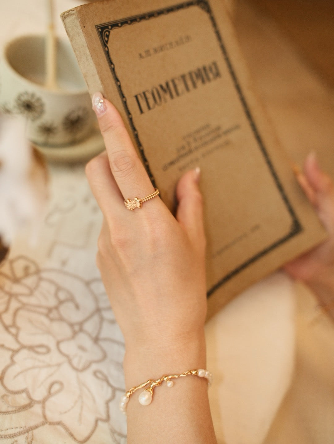 Gilded bow ring. Its crinkled texture brings an innate vintage charm, accented with dangling teardrop zircon stones that embody sophisticated grace.