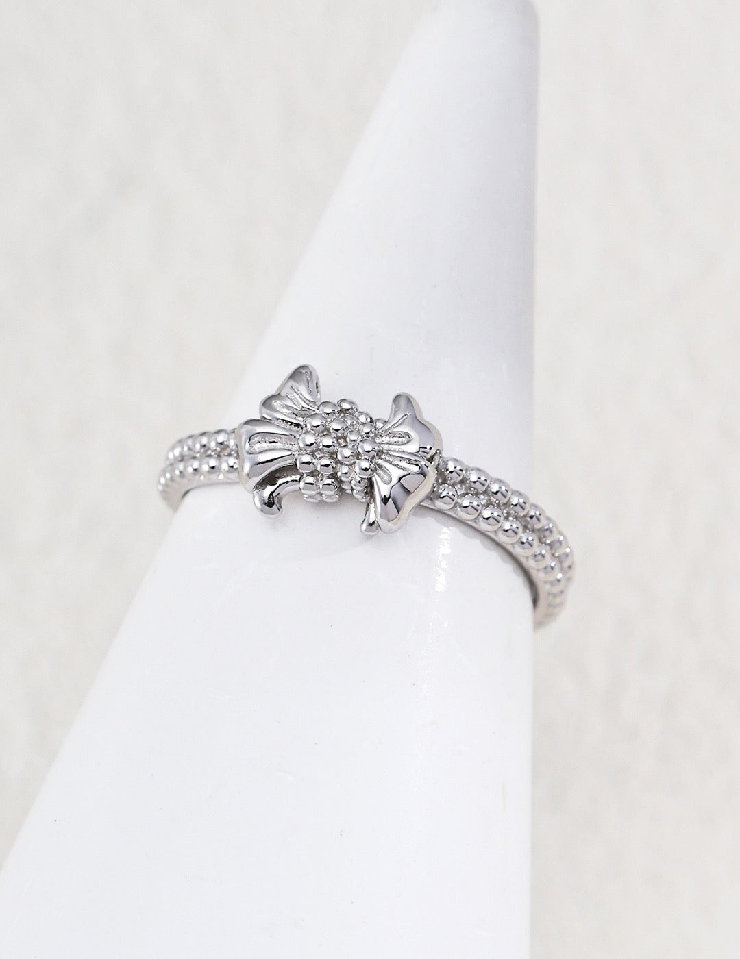 Gilded bow ring. Its crinkled texture brings an innate vintage charm, accented with dangling teardrop zircon stones that embody sophisticated grace.